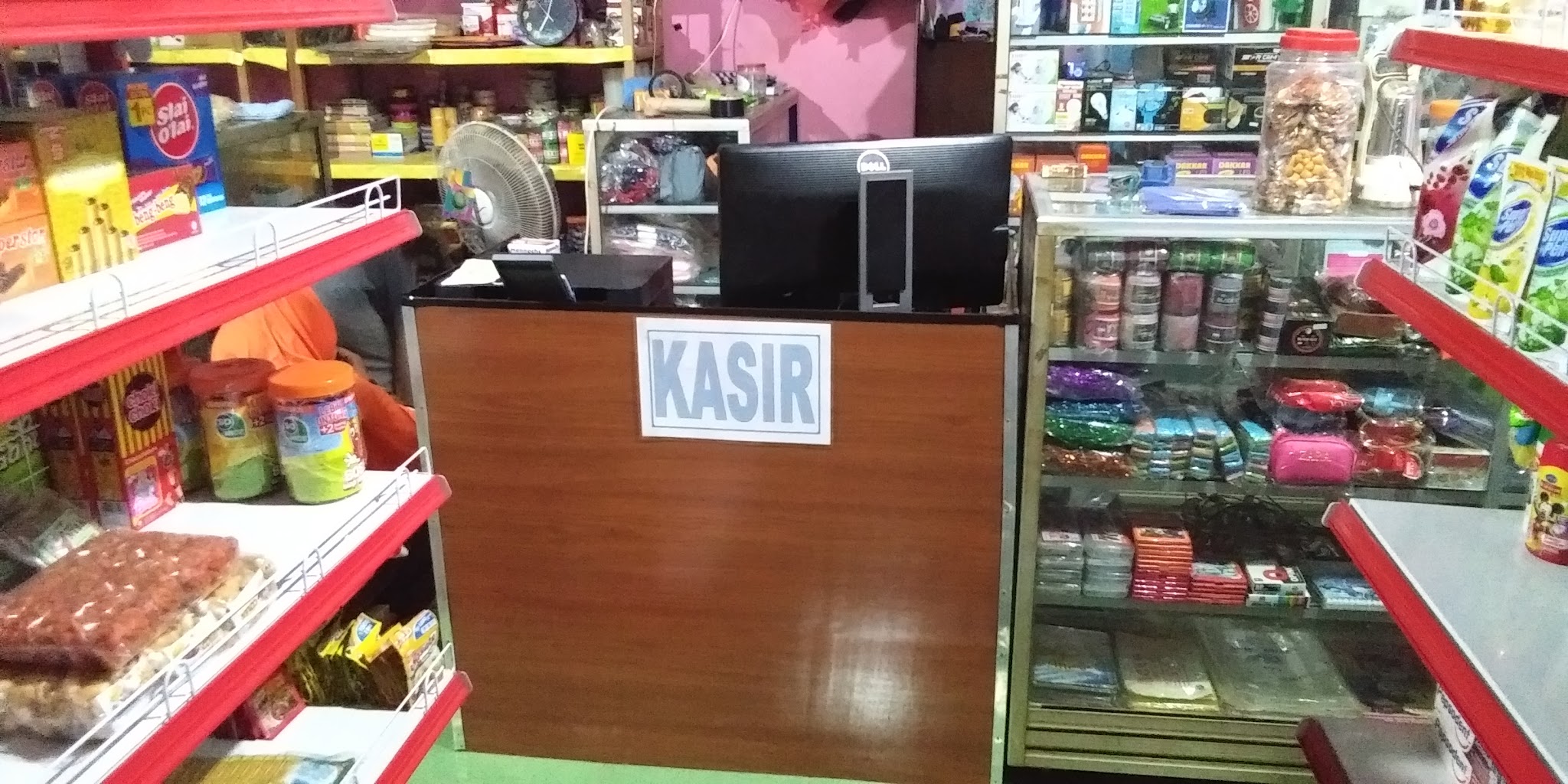 Etalase kaca benang jahit, dompet, dan makanan ringan
